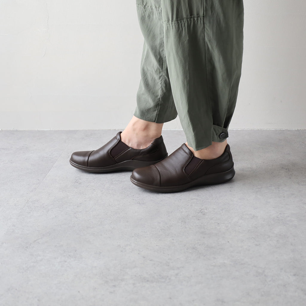 Best Shoes to Buy in Japan in 2026: 10 Japanese Brands Worth Shopping 9 Coffee-brown Achilles Sorbo leather slip-on comfort shoes worn with cropped trousers